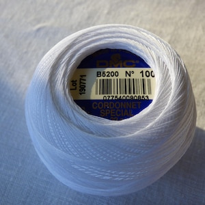 Peut inclure: Une pelote blanche de fil à broder DMC Cordonnet Special, étiquetée avec le logo DMC, le numéro de lot 190771, le numéro de couleur B5200 et le numéro 100.