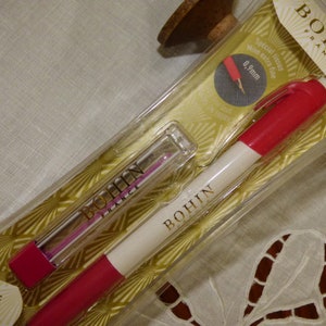 Peut inclure: Un ensemble de craie mécanique Bohin France, comprenant un crayon rouge et blanc et une recharge. L'emballage transparent met en valeur le produit. Le crayon a une mine extra fine de 0,9 mm.