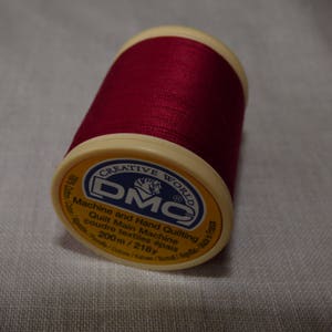 Può includere: Un'bobina di filo rosso con un'etichetta bianca che recita "CREATIVE WORLD DMC Machine and Hand Quilting Quilt Main Machine Coudre textiles épaisaiah 200m / 218y"