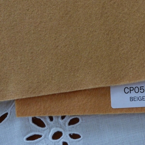 Puede incluir: Muestra de tela de fieltro beige con una etiqueta que dice "CP058 BEIGE".