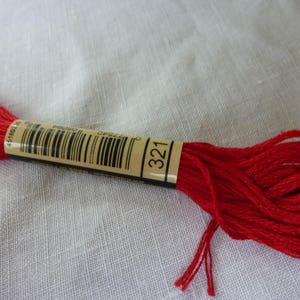 Op de afbeelding: Een spoel rood borduurgaren met een label met de tekst "DMC 321".