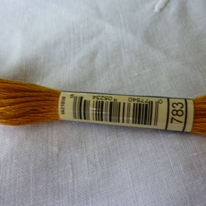 May include: A spool of embroidery floss in a deep orange colour. The label reads "783" and has a barcode. The label also includes the number "0621039".