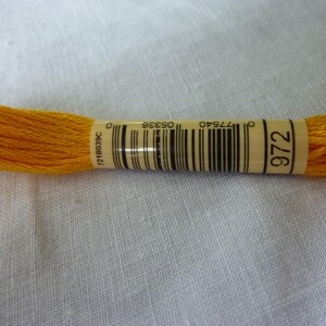 Op de afbeelding: Een spoel met felgele borduurgaren met het nummer 972 op het etiket. Het etiket bevat ook een barcode en het nummer 7218039C.