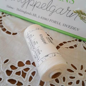 以下が含まれることがあります： 手書き風の「Welcome」の文字が入った、白く塗装された素朴な木製サイン。 表面は使い古したような加工が施され、隅には装飾的な花の要素があります。 背景は、ぼやけた木材の質感です。