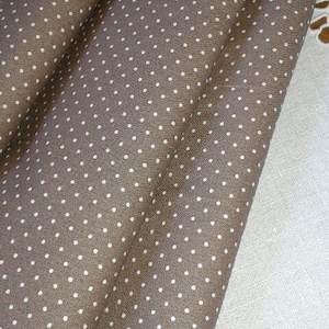 Peut inclure: Tissu marron à pois blancs. Le tissu est plié en trois.