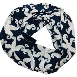 May include: A navy blue infinity scarf with a white starfish pattern. The scarf has a small black tag with the word "PASSPORT" printed on it.