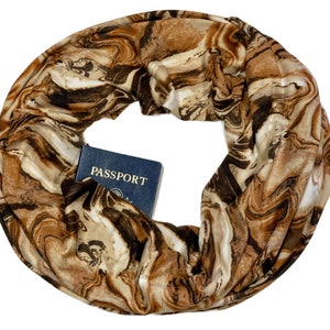 May include: A brown, white, and black patterned infinity scarf with a blue passport tucked inside. The passport has the word "PASSPORT" printed on the cover.