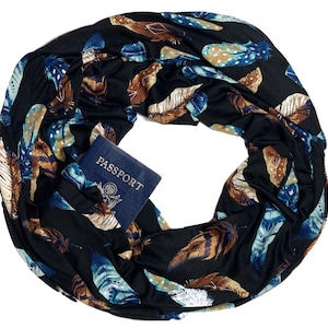 May include: Black infinity scarf with a feather pattern in shades of blue, brown, and white. A blue passport with the word "PASSPORT" is tucked inside the scarf. The scarf is made of a soft, flowing fabric.