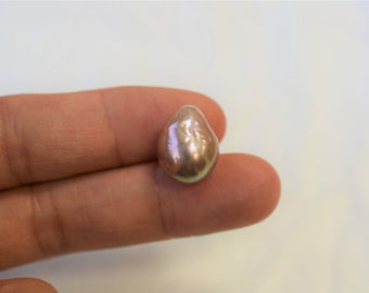 May include: A large, iridescent, baroque pearl with a pink and green hue.