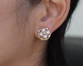 May include: A pair of gold earrings with a cluster of five white pearls and small diamonds set in a floral design.