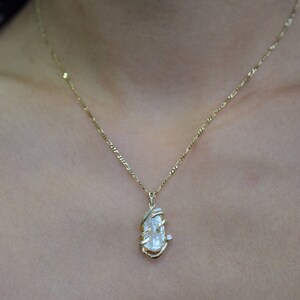 May include: A gold chain necklace with a delicate pendant featuring a large, clear, faceted gemstone.