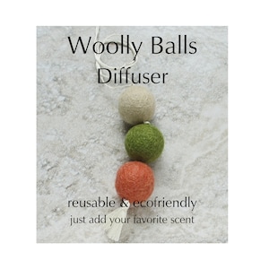 May include: A woolly ball diffuser with three colorful felt balls: cream, green, and orange. The text reads "Woolly Balls Diffuser" and "reusable & ecofriendly just add your favorite scent."