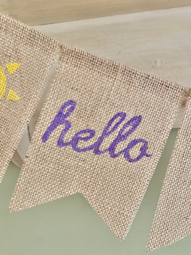 May include: A burlap banner with the word "hello" written in purple paint.