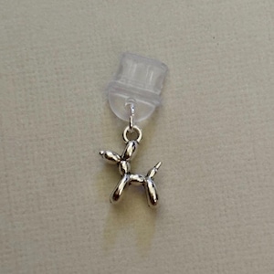 May include: A silver balloon animal charm in the shape of a dog, attached to a clear plastic charm holder.