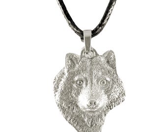 May include: A silver-toned metal pendant shaped like the head of a wolf, featuring detailed fur texture and forward-facing eyes. The pendant is suspended from a simple black cord necklace, creating a contrast between the metallic silver and the dark cord.