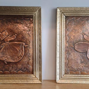 May include: Two framed copper wall hangings with embossed images of dancers. The frames are gold with ornate details.