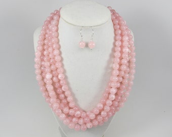 May include: A multi-strand pink rose quartz necklace with matching earrings. The necklace is made of round beads and is approximately 18 inches long. The earrings are also made of round beads and are approximately 1 inch long.