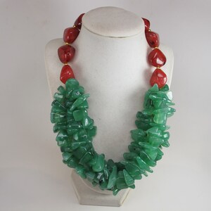May include: A green and red gemstone necklace. The necklace is made of small, irregular green stones and larger, smooth red stones.