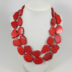 May include: A red stone necklace with irregular shaped beads. The necklace is double-stranded and has a silver clasp.