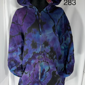 May include: A tie-dye hoodie in shades of purple, blue, and black. The zip-up sweatshirt has a hood and front pockets. The size is XL, and the number 283 is printed on the garment.
