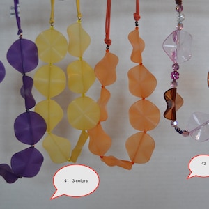 May include: A collection of colorful necklaces with large, irregularly shaped beads. The necklaces are in shades of purple, yellow, orange, and pink. The image includes text that says "41 3 colors" and "42".