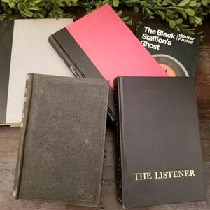 May include: A collection of five vintage hardcover books with black and white covers. The books are titled "The Black Stallion's Ghost" by Walter Farley, "The Listener", "The World's Medical Classics", and two other books with titles that are not visible.