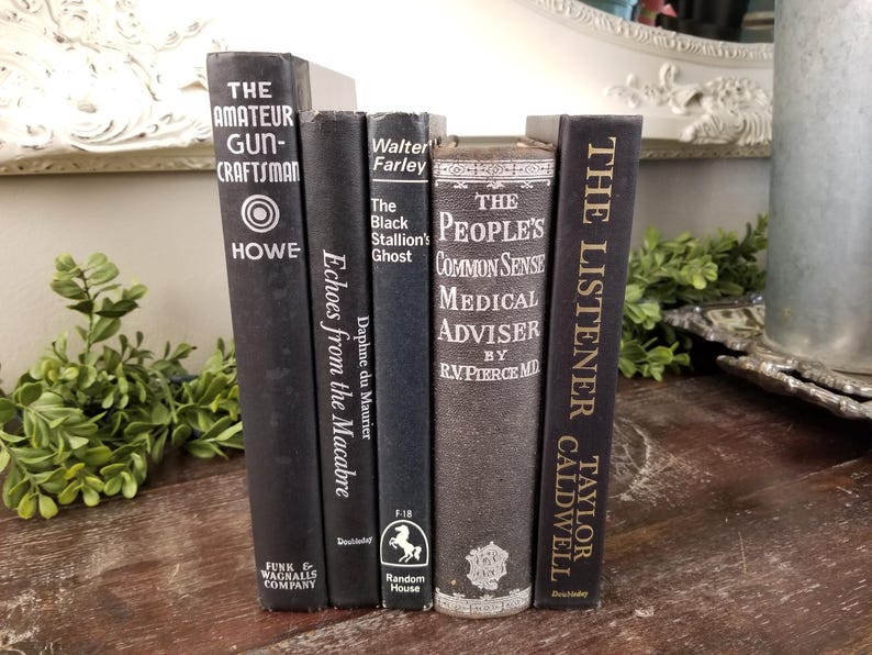 May include: A stack of six black hardcover books with white lettering on the spines. The titles include "The Amateur Gun-Craftsman", "Echoes from the Macabre", "The Black Stallion's Ghost", "The People's Common Sense Medical Adviser", and "The Listener".