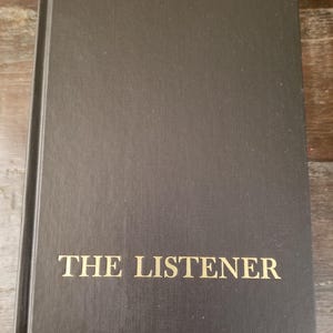 May include: A black hardcover book with the title "THE LISTENER" printed in gold lettering on the front cover.