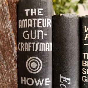 May include: Close-up of three black hardcover books with white text. The first book is titled "The Amateur Gun-Craftsman" with a silver circle logo and the author's name "HOWE". The second book is titled "Echoes" and the third book has the title "The Best Stories of G"