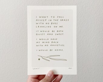 May include: A rectangular art print with a light green background and handwritten text. The text reads "I WANT TO FALL ASLEEP IN THE GRASS WITH NO BUGS CRAWLING ON ME... I WOULD BE HOME." A small green dot and leaf illustration are at the bottom.