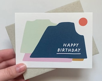 May include: A white card with a blue, green, pink, and gold abstract design. The card says "Happy Birthday" in white text.