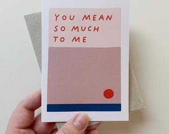 May include: A pink and white card with the text "YOU MEAN SO MUCH TO ME" in red. A red circle is in the bottom center of the card.
