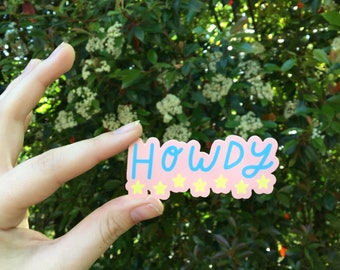 May include: A pink sticker with the word "Howdy" written in blue cursive lettering. Five yellow stars are below the word.