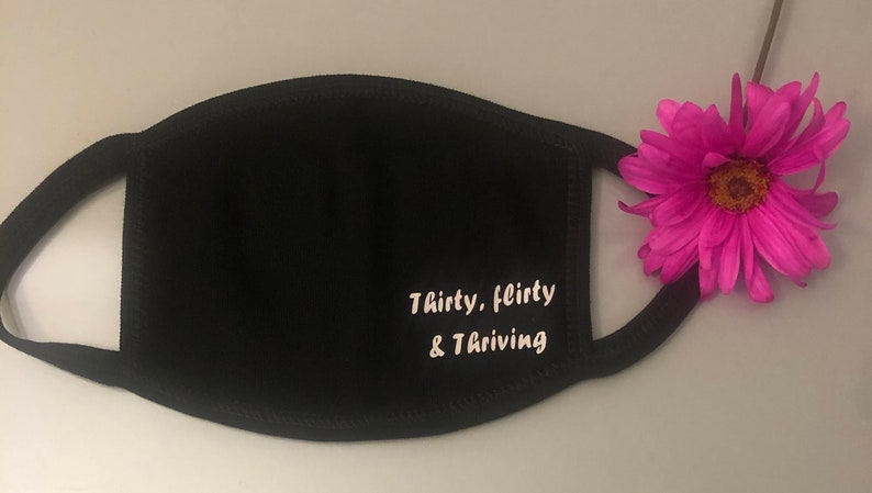May include: Black face mask with white text that reads "Thirty, flirty & thriving".