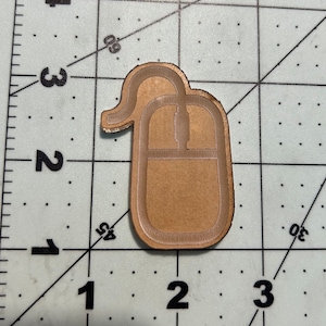 May include: A brown wooden cutout of a computer mouse. The mouse is a simple design with a single button and a scroll wheel.