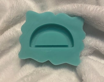 May include: A light blue silicone mold with a wavy edge. The mold is shaped like a half circle with a straight line across the bottom.