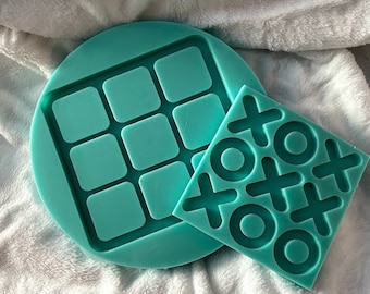 May include: Two teal silicone molds for making resin crafts. One mold is a tic-tac-toe board and the other is a nine-square grid.