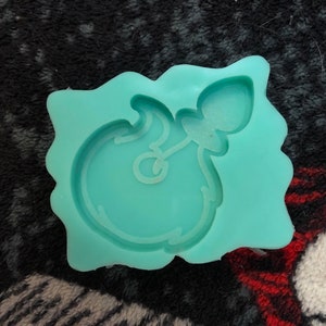 Può includere: Uno stampo in silicone blu turchese per realizzare oggetti in resina. Lo stampo ha la forma di una bottiglia di cartone animato con un tappo di sughero.