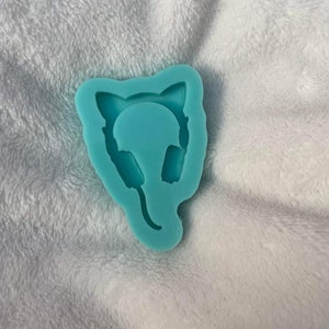 May include: A light blue silicone mold shaped like a cat wearing headphones. The mold is designed for making resin crafts.