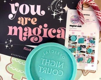 May include: A teal blue silicone mold with the text "COURT NIGHT" in white lettering. The mold is on a white background with gingerbread cookies and a candy cane.