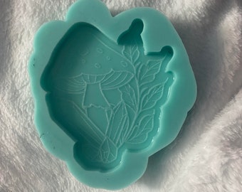 May include: A light blue silicone mold with a detailed design of a mushroom with leaves and a crystal. The mold is perfect for making resin crafts.