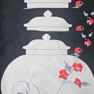 May include: Abstract textile art featuring white jar shapes on a black background. Red floral details and grey stems and leaves provide colour. The artwork is signed in the lower left corner.