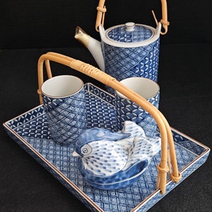 May include: A blue and white porcelain tea set with a bird design. The set includes a teapot, two cups, and a tray with a bamboo handle.