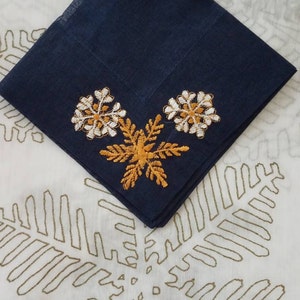 May include: A navy blue cotton handkerchief with white and gold embroidered snowflakes.