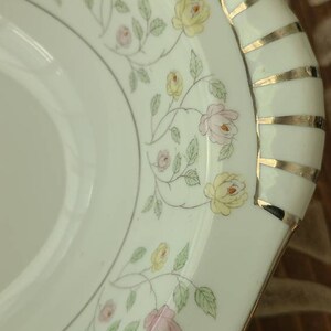 May include: White oval serving dish with a gold trim and a floral pattern of pink and yellow roses with green leaves.