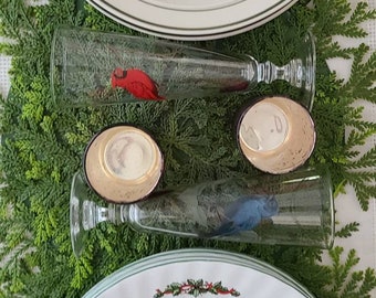 May include: A festive Christmas table setting featuring two white oval platters and two champagne flutes. The platters have a green border and a Christmas tree design. The flutes have bird designs.