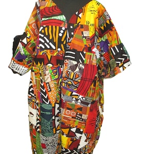 May include: A colorful patchwork dress with a V-neck and short sleeves. The dress features a vibrant mix of geometric and abstract patterns in red, yellow, black, and green. The dress is displayed on a black mannequin.