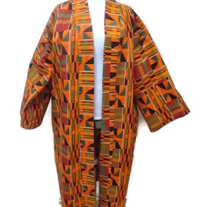 May include: A long, open-front cardigan with a colorful geometric pattern in shades of orange, yellow, green, red, and black. The cardigan is made of a woven fabric and has a relaxed fit.