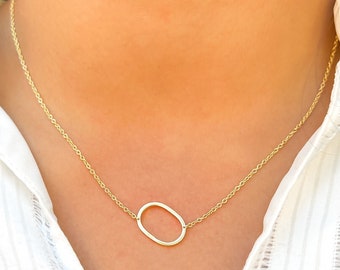 May include: A gold chain necklace with a simple oval pendant.
