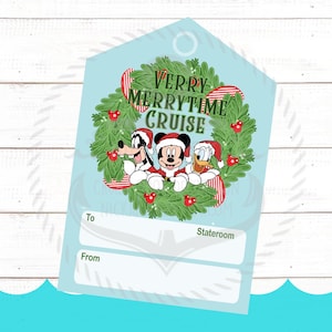 Op de afbeelding: Een lichtblauw rechthoekig cadeaulabel met een puntige bovenkant, voorzien van een groene krans met rode bessen en de tekst Very Merrytime Cruise. Mickey Mouse, Goofy en Donald Duck dragen kerstmutsen. Bevat velden voor To, From en Stateroom.